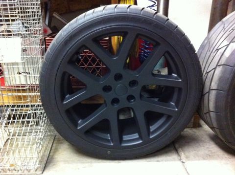 2010 Dodge Challenger - A black multi-spoke wheel and tire are shown, with another tire visible to the right.