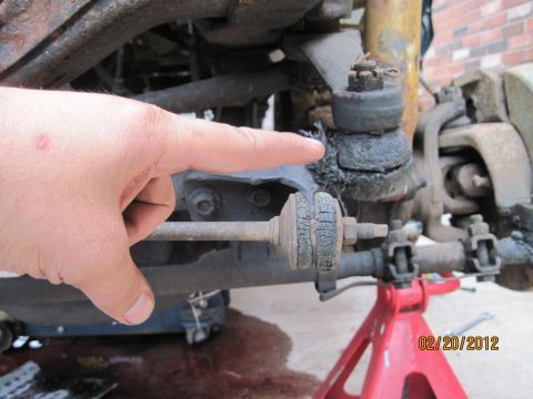 1979 Ford Bronco - Close-up of a damaged vehicle suspension component, with a hand indicating the issue.