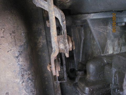 1979 Ford Bronco - A close-up, low-angle shot shows rusty linkage components attached to a dark, greasy transmission housing. A date stamp of "02/20/2012" is…