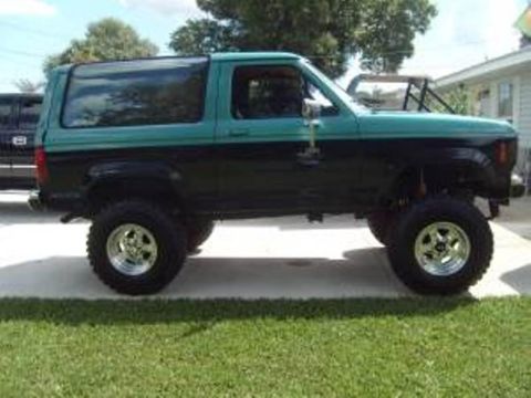 1999 Ford Ranger - Side view of a lifted two-tone green and black Ford Bronco II parked on a driveway.