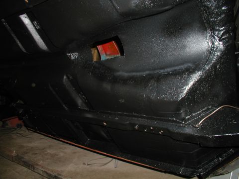 1960 Ford Ranchero - The underside of a vehicle is coated in black, revealing its structural components and a small access hole.
