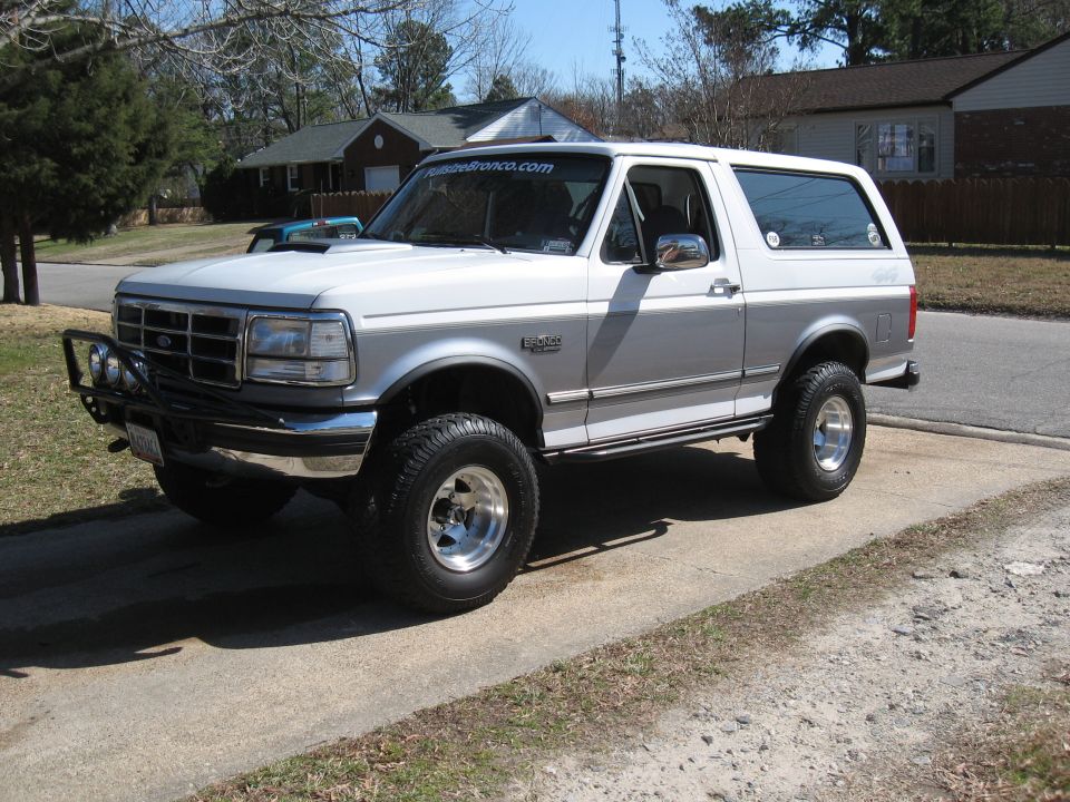Lifted two-tone silver and white Ford Bronco with aftermarket bumper and off-road tires parked on a driveway