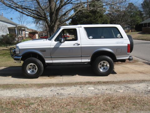 1994 Ford Bronco - Side view of a two-tone white and silver Ford Bronco parked on a driveway.