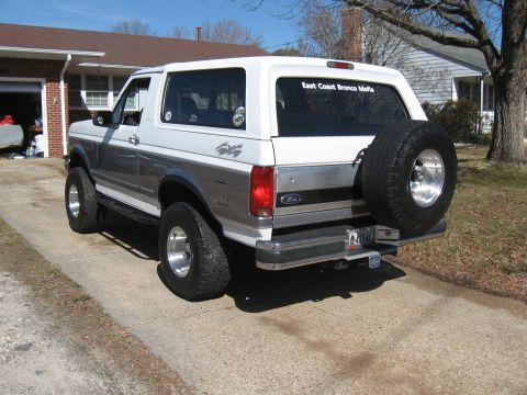 1994 Ford Bronco - Rear view of a two-tone 1994 Ford Bronco with a spare tire on the tailgate and 'East Coast Bronco Mafia' sticker.