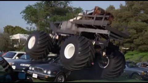 1993 Ford Taurus - A monster truck is shown crushing two cars under its massive tires.