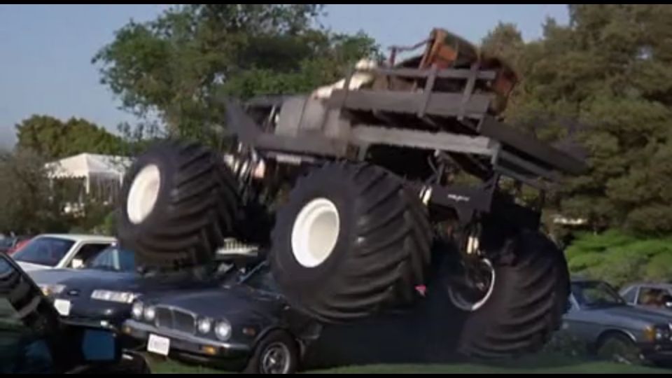 Monster truck on top of two cars, crushing them