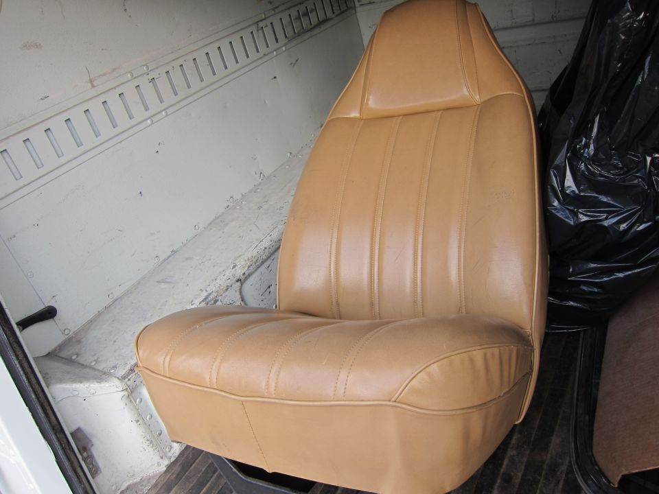 Tan vinyl seat with vertical stitching in a cargo van interior