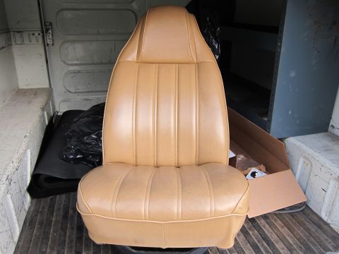 1987 Dodge 1500 - Bucket seat with tan vinyl upholstery, likely from a van or truck, stored in the cargo area.