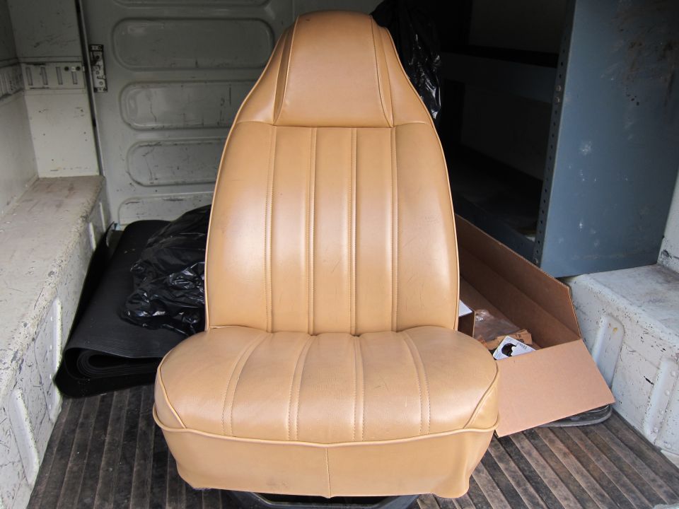 Tan vinyl bucket seat with vertical pleats on the back and horizontal pleats on the cushion, inside a van