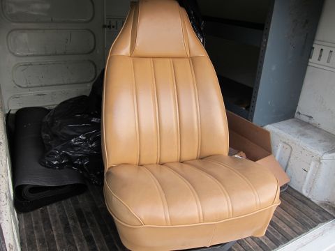 1987 Dodge 1500 - A single tan bucket seat is shown inside a vehicle, with various items stored in the background.