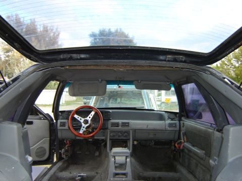 1987 Ford Mustang - The interior of a 1987 Ford Mustang shows an aftermarket steering wheel and a stripped-down cabin, suggesting a focus on performance.