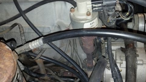 1992 Ford Bronco - Close-up view of engine components, including hoses and wiring, with a visible label.