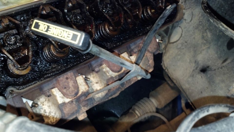 Engine bay showing valve cover, spark plugs, and an oil dipstick with "ENGINE OIL" text