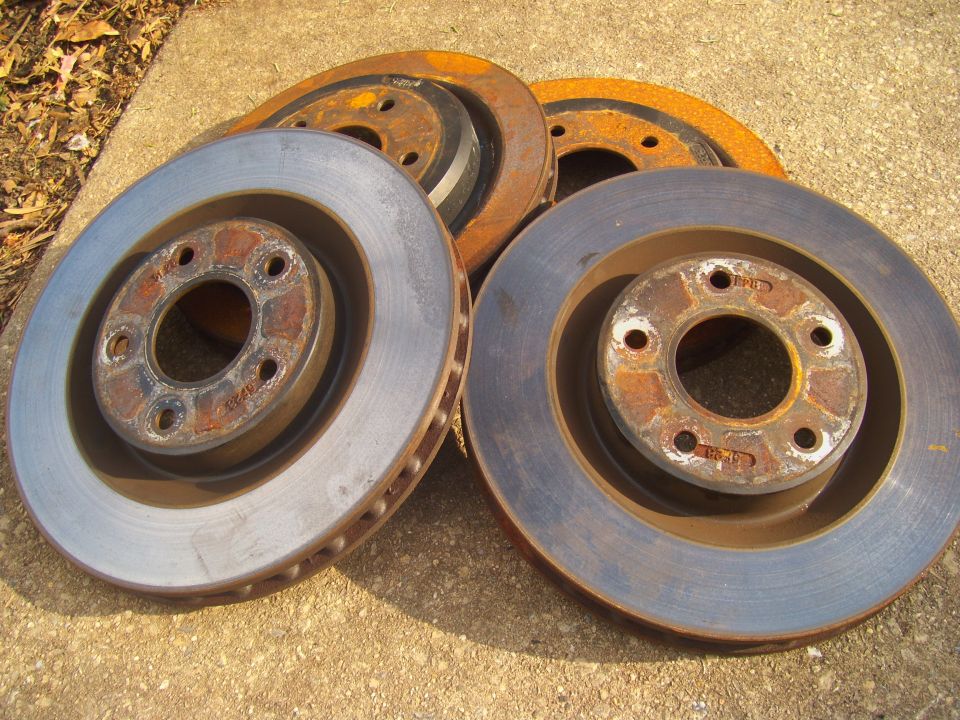 Several rusty brake rotors piled on concrete