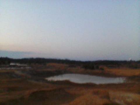 1996 Jeep Cherokee - A wide shot of a barren landscape with pools of water and uneven terrain under a hazy sky.