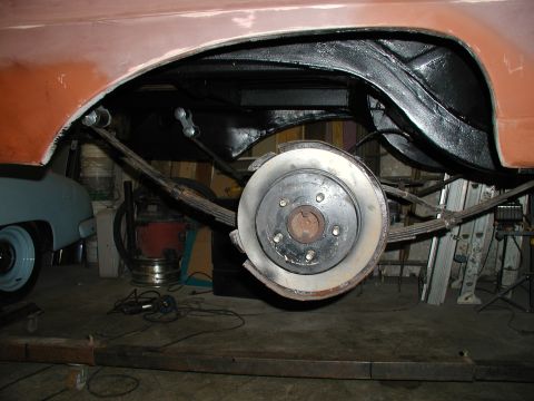 1960 Ford Ranchero - The rear suspension and wheel well of a 1960 Ford Ranchero, showing leaf springs and a brake rotor during restoration.