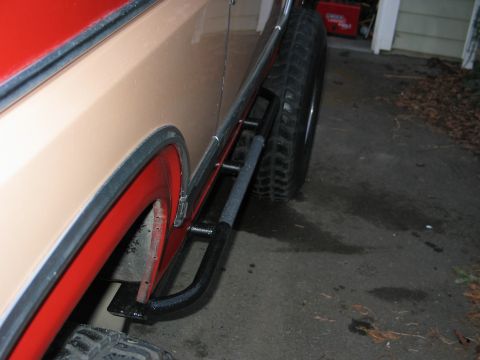 1984 Ford Bronco - 1984 Ford Bronco side profile with aftermarket rock sliders and red fender flares.