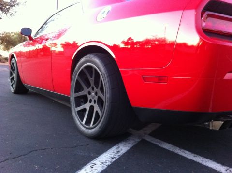 2010 Dodge Challenger - A red Dodge Challenger is parked, its custom wheels and rear profile.