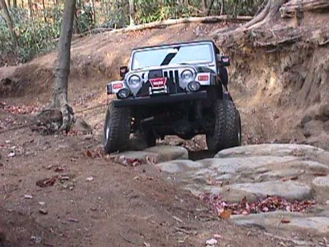 1996 Ford Bronco - A black Jeep Wrangler navigates a rocky off-road trail.