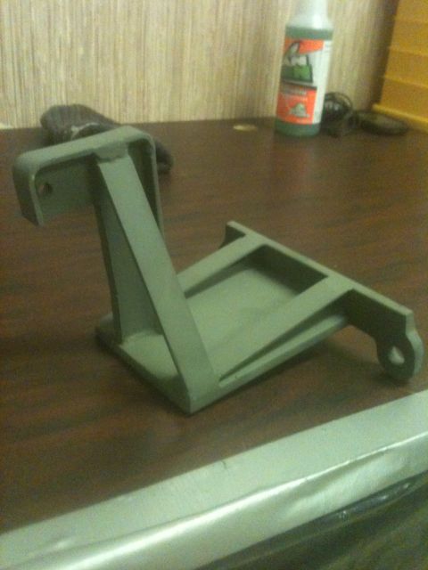 1993 Ford Bronco - A single metal bracket is shown resting on a desk, with a bottle of liquid in the background.
