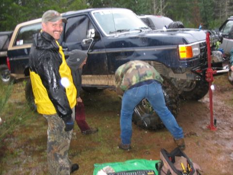 1995 Ford Bronco - A group of people are gathered around a lifted Ford Bronco in a muddy outdoor setting.