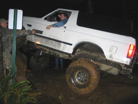 1995 Ford Bronco - 1995 Ford Bronco navigating a challenging muddy off-road course at night.