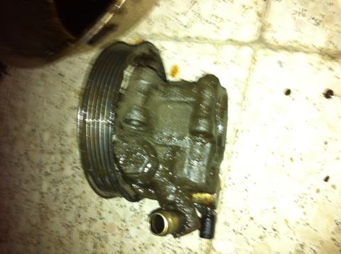 1998 Ford Crown Victoria - A greasy power steering pump, likely removed from a vehicle for repair or replacement, is shown with its pulley.