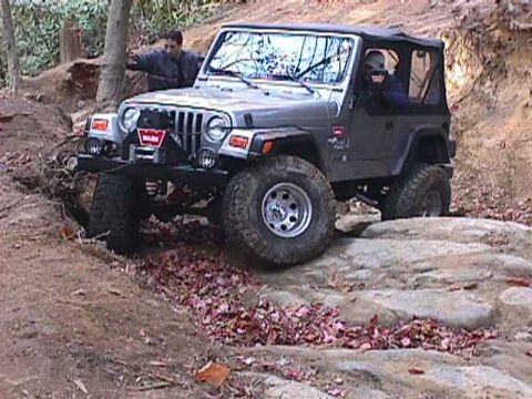 1996 Ford Bronco - Jeep Wrangler TJ tackles a challenging off-road trail with rocky obstacles.