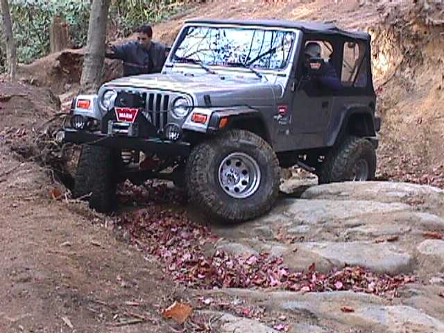 Jeep Wrangler TJ navigating rocky terrain with a person visible inside