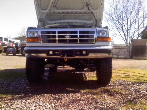 1996 Ford Bronco - Front view of a 1996 Ford Bronco with its hood up, parked outdoors with other vehicles nearby.