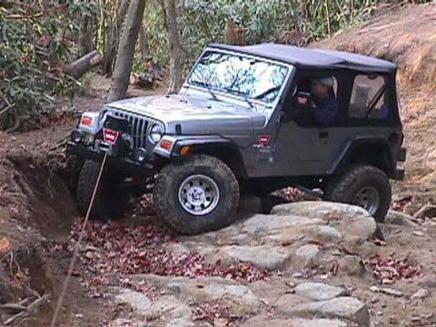 1996 Ford Bronco - A Jeep Wrangler TJ navigates a challenging off-road course with steep inclines and large rocks.
