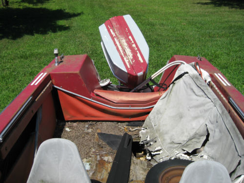 Red boat interior with outboard motor and torn cover