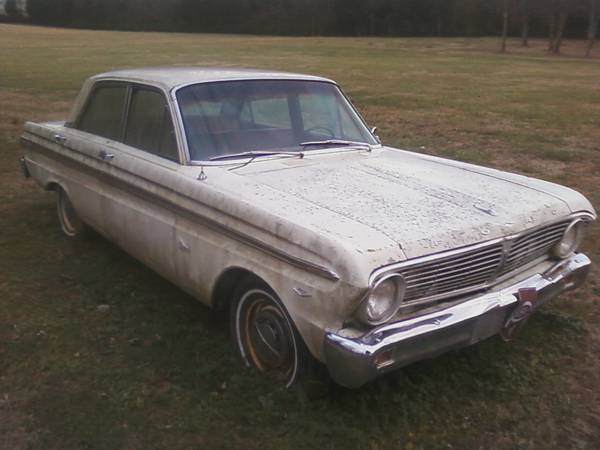 White sedan parked on grass, front quarter view. Chrome grille and bumper are visible