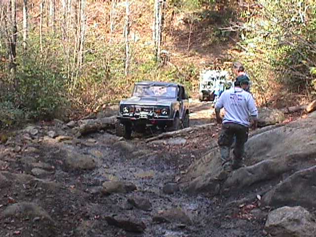 1996 Ford Bronco navigating a rocky, wooded trail with another vehicle behind it