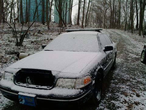 2001 Ford Crown Victoria - A white 2001 Ford Crown Victoria sits covered in snow, viewed from the front.