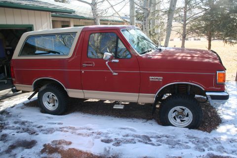 1990 Ford Bronco - This red Ford Bronco features a two-tone paint scheme and appears to be from the late 1980s.