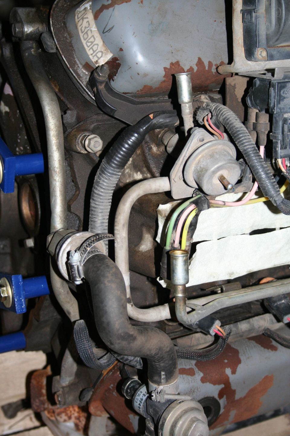 Engine components with hoses, wires, and a metal tag reading "0K360AA"
