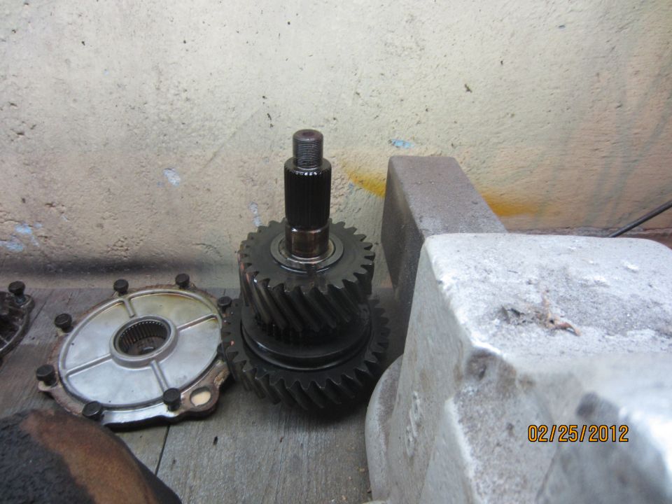 Gears and a metal plate with bolts on a wooden surface.