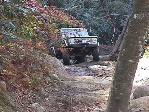 1996 Ford Bronco - Ford Bronco navigates a rough, unpaved path through a wooded area during autumn.