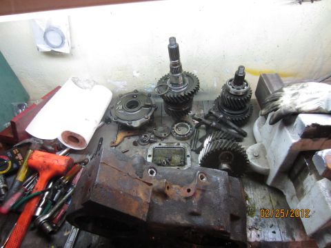 1979 Ford Bronco - A collection of gears and transfer case components are laid out on a workbench, ready for assembly or repair.