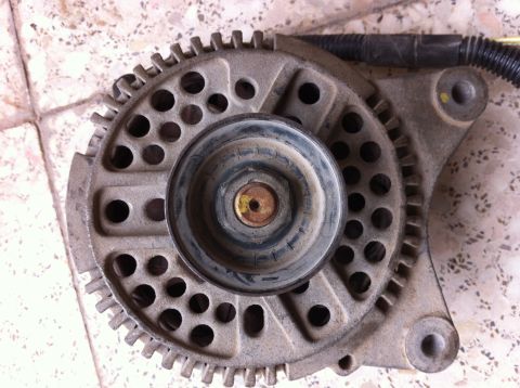 1998 Ford Crown Victoria - This is a close-up view of a vehicle alternator, a component not identifiable by year or make from this image alone.