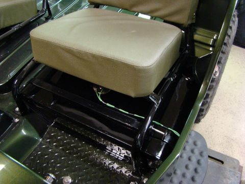 1948 Jeep Wrangler - Close-up view of the interior of a green vehicle, highlighting the tan seats and black metal flooring.