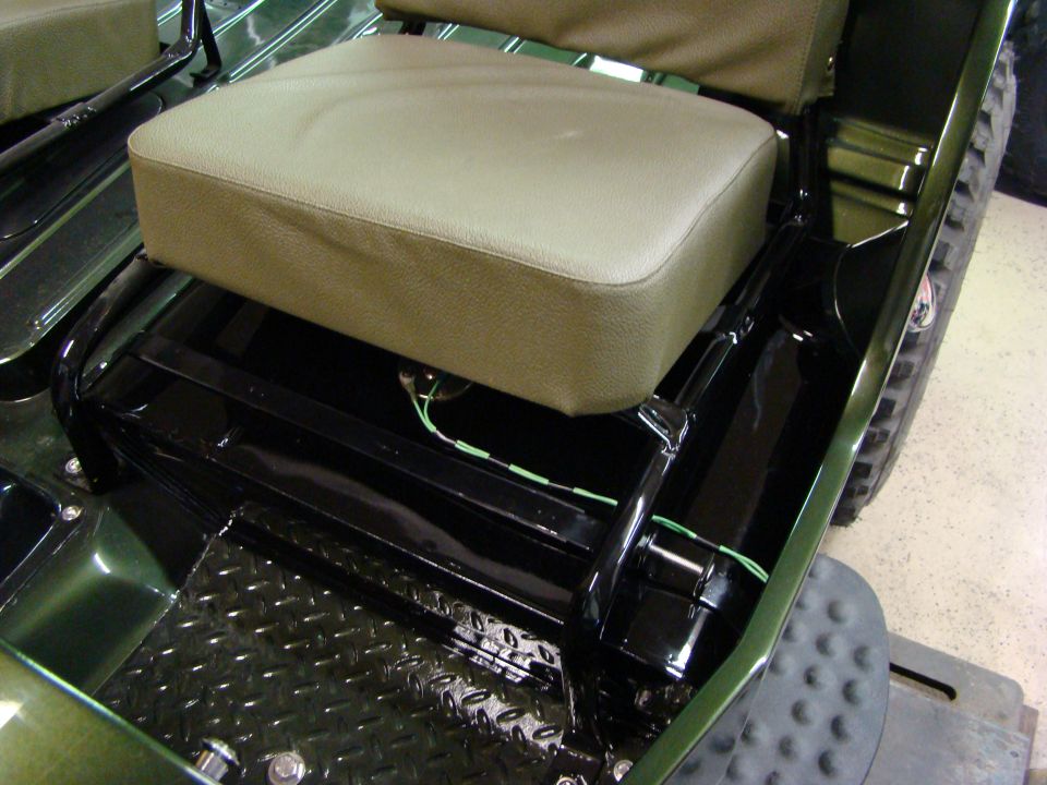 Interior of a green vehicle showing tan seats and black floor panels