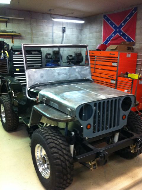 1948 Jeep Wrangler - This Jeep CJ-3A is undergoing restoration in a garage, with tools and a flag visible.