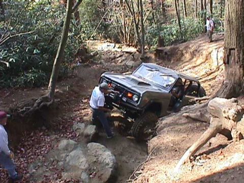 1996 Ford Bronco - A Ford Bronco attempts to climb a challenging off-road trail with another vehicle visible in the background.