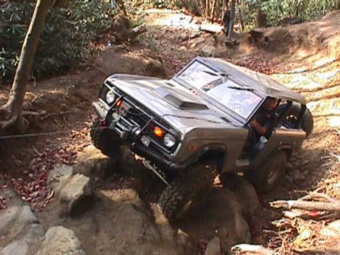 1996 Ford Bronco - A gray 1978 Ford Bronco tackles a rocky trail, demonstrating its off-road capabilities.