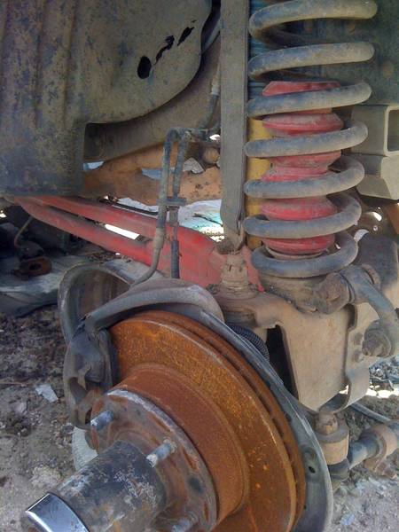 1979 Ford Bronco - Close-up view of a vehicle's front suspension components, including a brake rotor and coil spring.