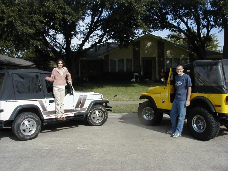 Two Jeep Wranglers, one white and one yellow, parked on a suburban street with people standing next to them