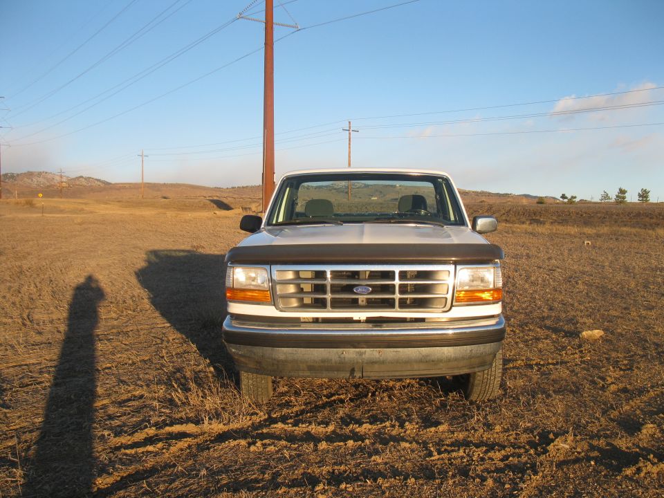 Front view of a 1992 Ford F-150 parked in a dry, grassy field with power lines overhead