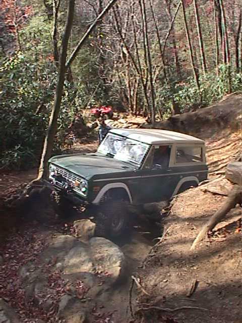 1996 Ford Bronco - Ford Bronco tackling a challenging off-road course in the woods.